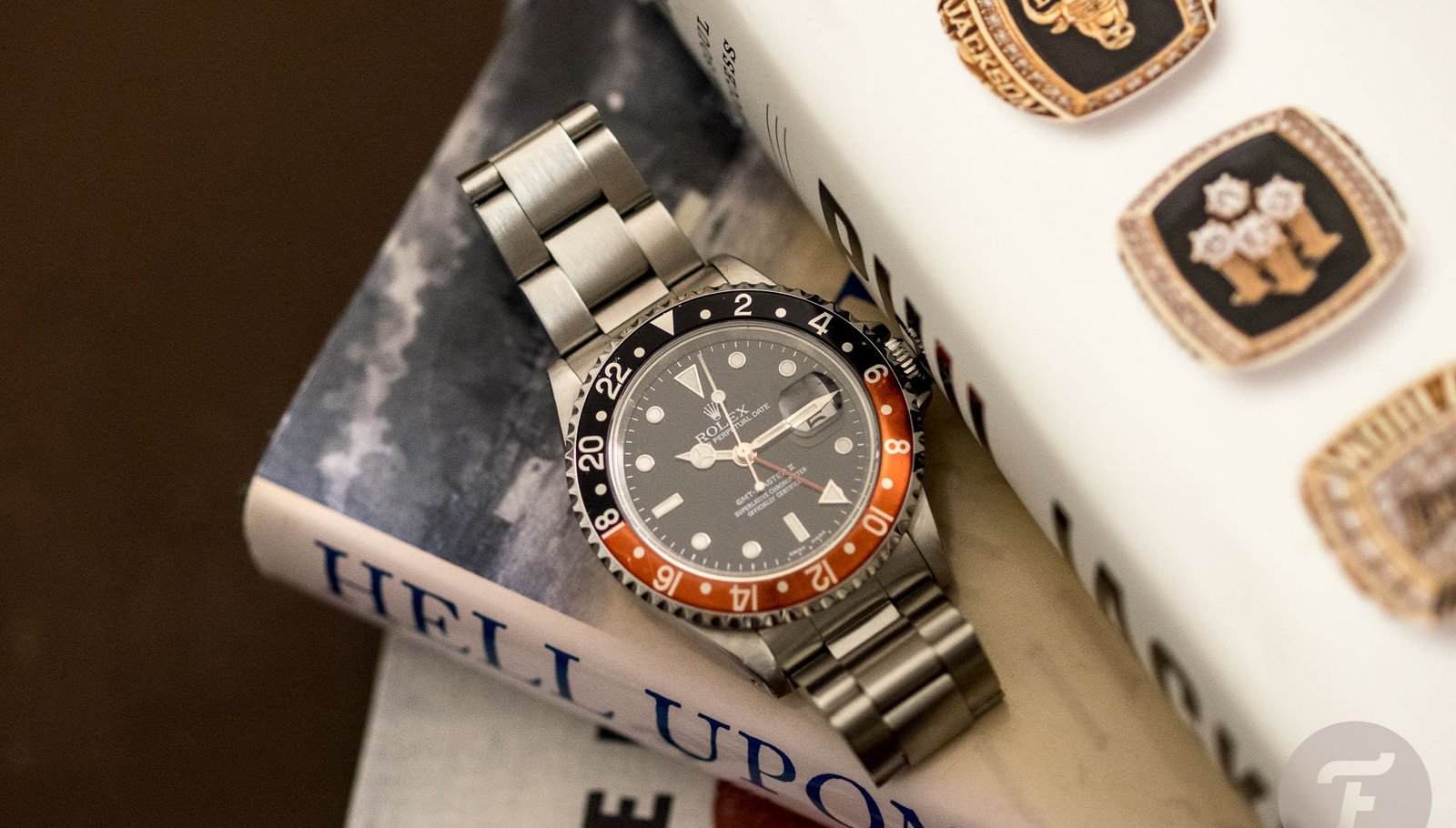 Rolex GMT-Master II wristwatch with black and red bezel beside luxury jewelry.