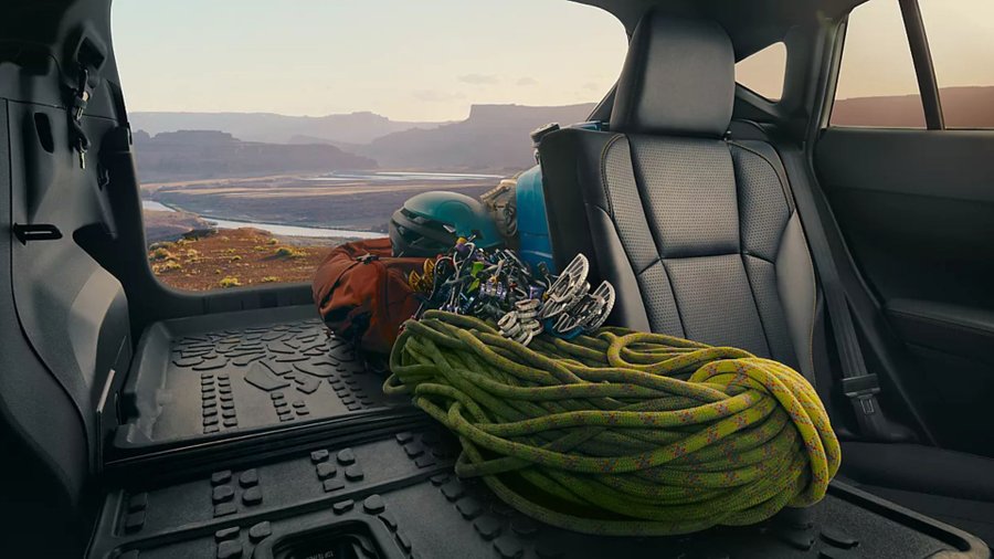 Rear cargo area of a Subaru Crosstrek filled with climbing gear, with a canyon landscape visible outside.