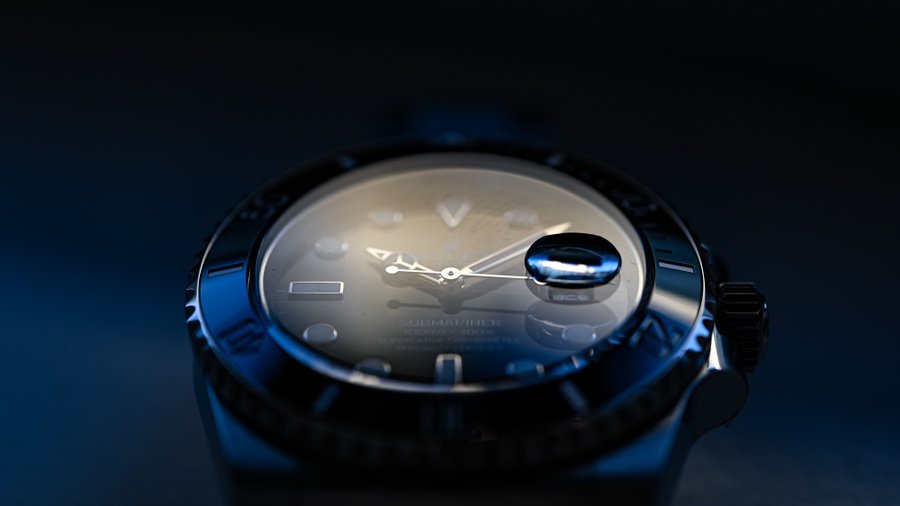 Macro close-up of a Rolex Submariner Date dial and cyclops under dark studio lighting
